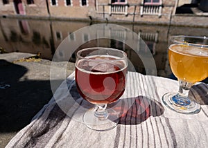 Tasting of Belgian beer on open cafe or bistro terrace with view on medieval houses and canals in Bruges, Belgium