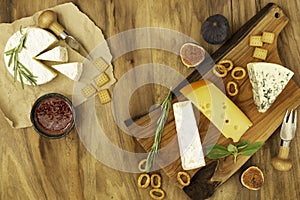Tasting cheese dish with herbs and fruits on wooden table. Food for wine and romantic, cheese delicatessen. Top view.