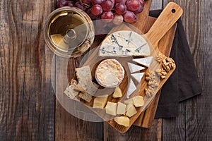 Tasting cheese dish on a wooden plate. Food for wine and romantic, cheese delicatessen on a wooden rustic table. Top view with cop