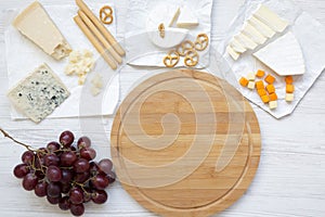 Tasting cheese with grapes, bread sticks, walnuts and pretzels on wooden background, top view. Food for romantic. Flat lay.