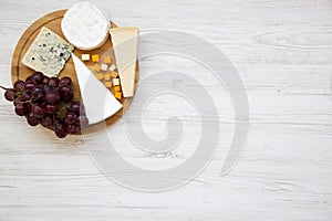 Tasting cheese with grapes on round wooden board. Food for wine, top view. Space for text. Flat lay.