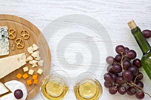 Tasting cheese with wine, grapes, walnuts and pretzels on wooden background. Food for romantic. From above. Top view. Flat lay.