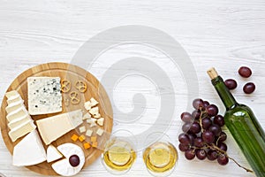 Tasting cheese with wine, grapes, walnuts and pretzels on wooden background. Food for romantic. From above. Top view. Flat lay.