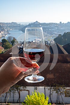Tasting of different fortified dessert ruby, tawny port wines in glasses with view on Douro river, porto lodges of Vila Nova de