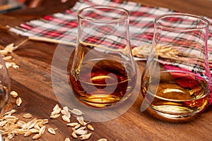Tasting of different Scotch whiskies strong alcoholic drinks, drum of whiskey and colorful Scotch tartan on background close up