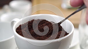 Tasting of fresh ground milled coffee in a white cup stirring with a teaspoon