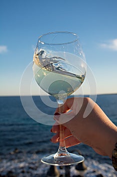 Tasting of glass of cold white wine on outdoor terrace with sea