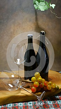 Tasting goblets with wine bottles, glass grapes, oak plank and vine branch