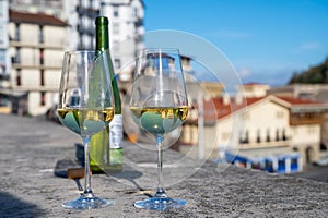 Tasting of txakoli or chacolÃ­ dry white wine produced in Spanish Basque Country with view on old port and