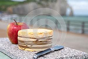 Tasting of yellow livarot cow cheese from Calvados region served with apple and view on alebaster cliffs Porte d`Aval in Etretat,