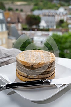 Tasting of yellow livarot cow cheese from Calvados region and view on old houses of Etretat, Normandy, France
