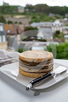 Tasting of yellow livarot cow cheese from Calvados region and view on old houses of Etretat, Normandy, France