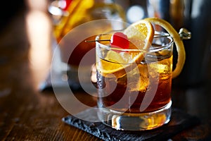 Tasty alcoholic old fashioned cocktail with orange slice, cherry, and lemon peel garnish