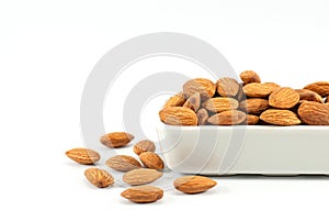 Tasty almonds are housed in white ceramic vessels and placed on a white background with copy space