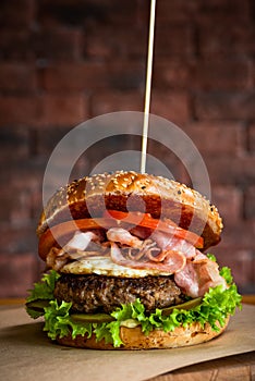 Tasty American Burger with BAcon Beef and Egg on Wooden Table. Brick Wall Copyspace Background