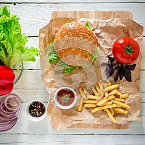 Tasty american hamburger with beef and french fries on wood background. Top view. Flat lay.