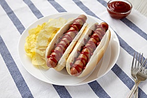 Tasty American Hot Dog with Potato Chips on a white plate, low angle view