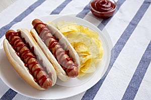 Tasty American Hot Dog with Potato Chips on a white plate, side view. Space for text