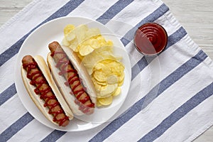 Tasty American Hot Dog with Potato Chips on a white plate, top view. Flat lay, overhead, from above