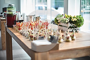 Tasty appetizers with wooden spoons served in glass jars on wooden table.