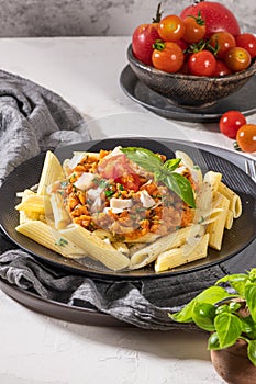 Tasty appetizing classic italian penne pasta with vegetarian lentil bolognese sauce, cheese parmesan and basil on plate on light