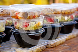 Tasty appetizing food in closed plastic transparent, black containers on table