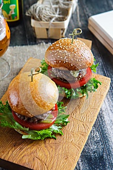 Tasty and appetizing hamburger cheeseburger on a wooden board side view