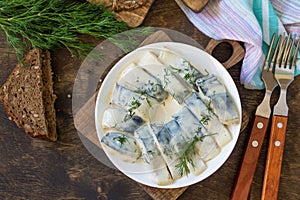 Tasty appetizing pickled mackerel in a sauce with spices on a dark rustic wooden table. Top view flat