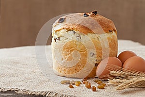 Tasty backed traditional russian kulich easter cake with raisins and eggs on vintage textile