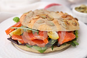 Tasty bagel with salmon and tomatoes on plate, closeup