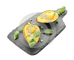Tasty baked avocado with eggs on slate board against white background