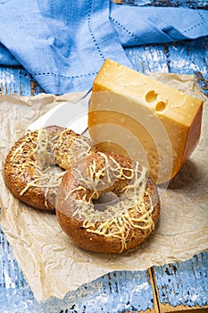 Tasty baked bagels with melted cheese and piece of aged Dutch Gouda cheese