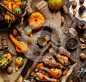 Tasty baked chicken drumsticks with pumpkin and red onion slices in baking ceramic pan