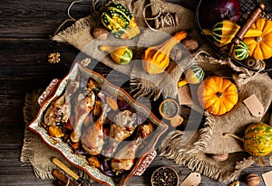 Tasty baked chicken drumsticks with pumpkin and red onion slices in baking ceramic pan