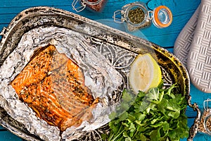 Tasty Baked Fish Salmon in Foil on Blue Table