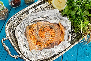 Tasty Baked Fish Salmon in Foil on Blue Table