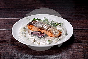 Tasty baked salmon fish on a white dish with broccoli and pea sprouts