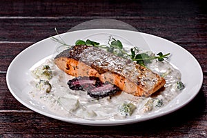 Tasty baked salmon fish on a white dish with broccoli and pea sprouts