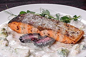 Tasty baked salmon fish on a white dish with broccoli and pea sprouts