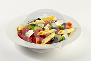 Tasty beautiful greek traditional greek or italian salad with vegetables and pasta on plate. Bright Background.