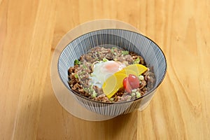 Tasty beef Gyudon with fried rice, egg and onion in a bowl on wooden background top view of japanese food