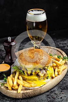 Tasty big burger and beer glass on wood tray. American food concept. fast food meal. banner, menu, recipe, place for text