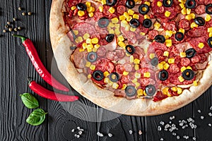 Tasty and big pizza with different types of meat. Pizza with sausage, ham, corn and olives