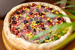 Tasty and big pizza with different types of meat. Pizza with sausage, ham, corn and olives