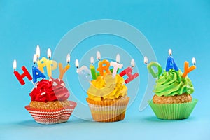 Tasty birthday cupcakes with candles on color background