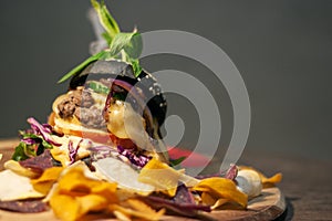 Tasty Black burger with meat patty, cheese, tomatoes, mayonnaise, purple and orange sweet potato, taro Crisps