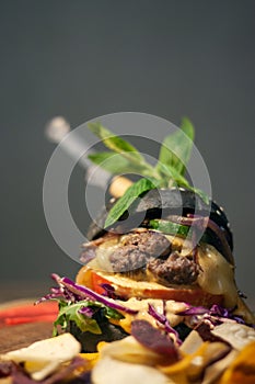 Tasty Black burger with meat patty, cheese, tomatoes, mayonnaise, purple and orange sweet potato, taro Crisps