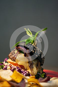 Tasty Black burger with meat patty, cheese, tomatoes, mayonnaise, purple and orange sweet potato, taro Crisps