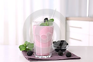 Tasty blackberry milk shake with fresh berries on table