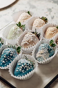 Tasty Blue chocolate dipped strawberries with sugar sprinkles on a parchment paper